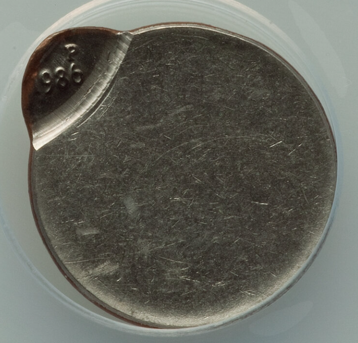 1986 Roosevelt dime showing off-center strike error with design shifted and blank planchet crescent visible